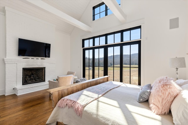 bedroom with a fireplace, dark wood-type flooring, a mountain view, beam ceiling, and high vaulted ceiling