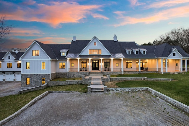 modern inspired farmhouse with a porch, a lawn, and a garage