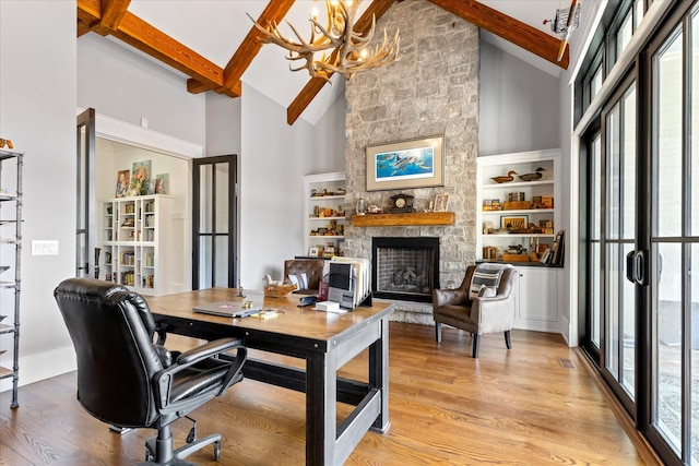 office space featuring an inviting chandelier, light hardwood / wood-style flooring, a fireplace, high vaulted ceiling, and beamed ceiling