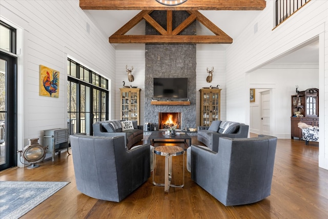 living room featuring beamed ceiling, plenty of natural light, a fireplace, and wood-type flooring