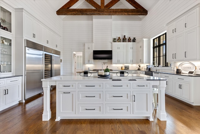 kitchen featuring beamed ceiling, a kitchen breakfast bar, a kitchen island, and built in fridge