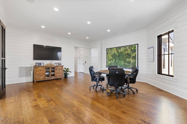 dining area with a healthy amount of sunlight, hardwood / wood-style flooring, ornamental molding, and wood walls