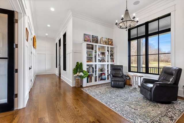 sitting room with a chandelier, ornamental molding, and wood-type flooring