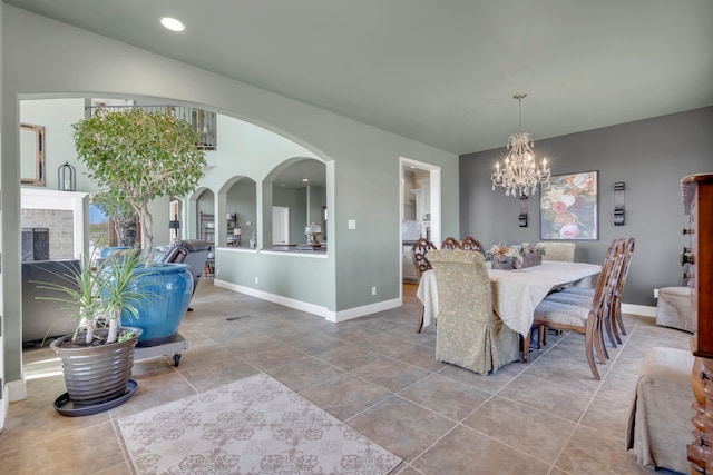 tiled dining space featuring a fireplace and a chandelier