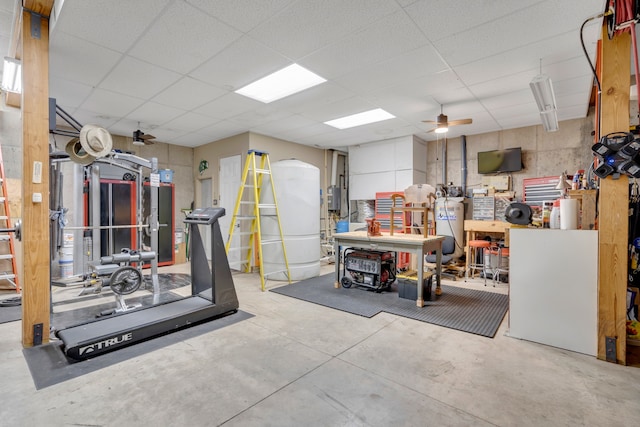 exercise area featuring ceiling fan, a paneled ceiling, and a workshop area