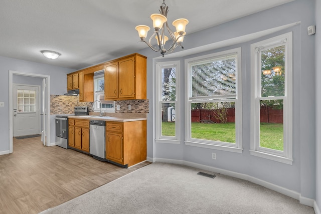 kitchen featuring light carpet, a healthy amount of sunlight, stainless steel dishwasher, and range with electric cooktop