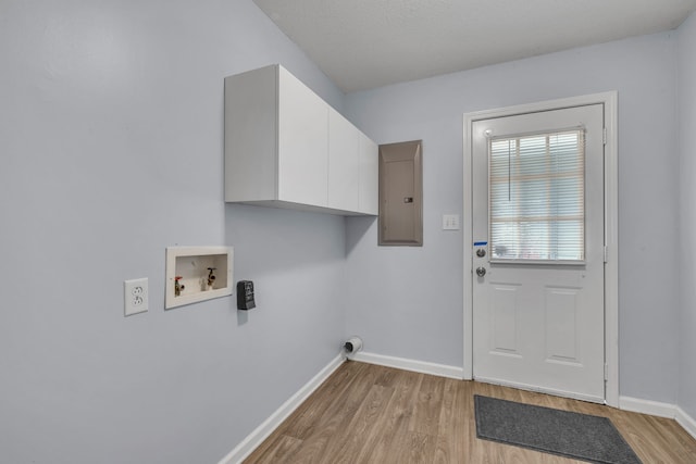 laundry room with washer hookup, light hardwood / wood-style floors, and cabinets