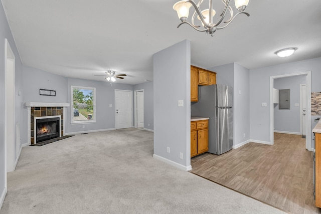 unfurnished living room with a fireplace, ceiling fan with notable chandelier, and light colored carpet