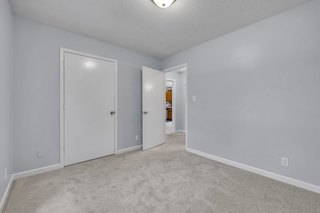 unfurnished bedroom featuring a textured ceiling and light colored carpet