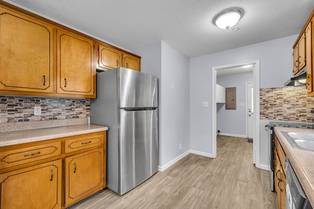 kitchen featuring backsplash, stainless steel appliances, a textured ceiling, and light wood-type flooring