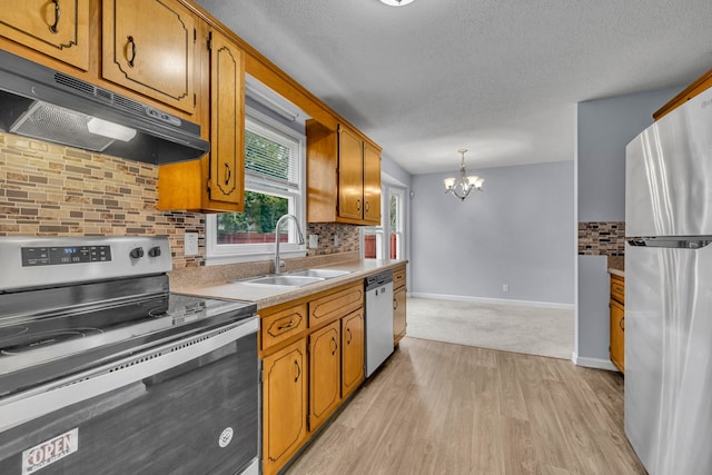 kitchen featuring hanging light fixtures, a notable chandelier, light wood-type flooring, stainless steel appliances, and tasteful backsplash