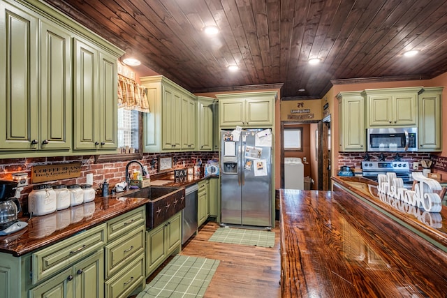 kitchen with green cabinets, stainless steel appliances, light wood-type flooring, and sink