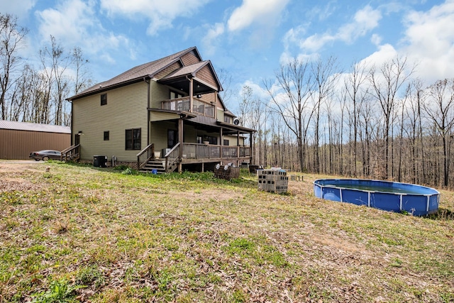 back of house with a balcony, a yard, and a swimming pool side deck