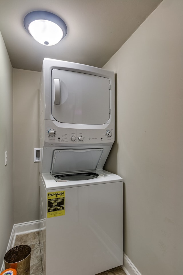 laundry room featuring light tile floors and stacked washer / dryer