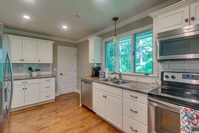 kitchen with white cabinets, appliances with stainless steel finishes, pendant lighting, light wood-type flooring, and tasteful backsplash