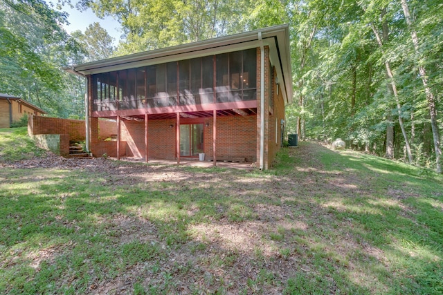 back of property with a yard, a patio area, and a sunroom