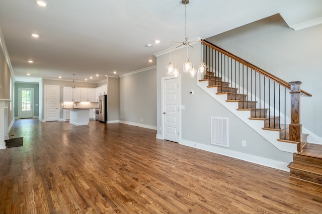 unfurnished living room featuring ornamental molding, a notable chandelier, and hardwood / wood-style floors