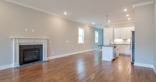 unfurnished living room with sink, ornamental molding, and dark wood-type flooring