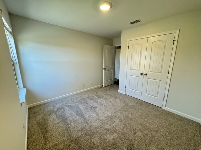 unfurnished bedroom with baseboards, carpet, visible vents, and a closet