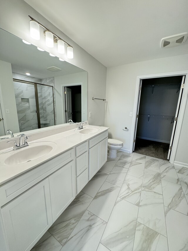 bathroom with double vanity, marble finish floor, a sink, and a stall shower