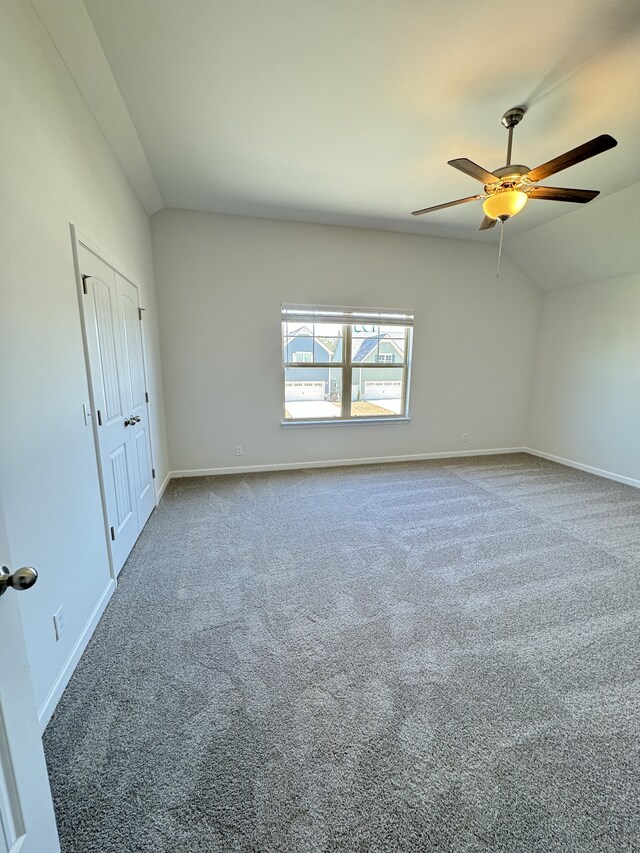 unfurnished room featuring lofted ceiling, baseboards, carpet floors, and ceiling fan