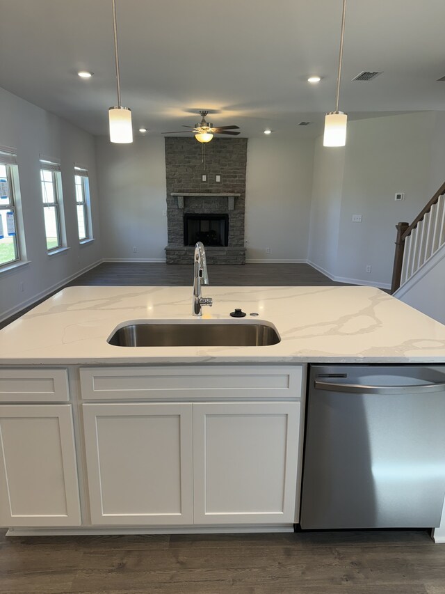 kitchen with a sink, visible vents, white cabinets, open floor plan, and stainless steel dishwasher