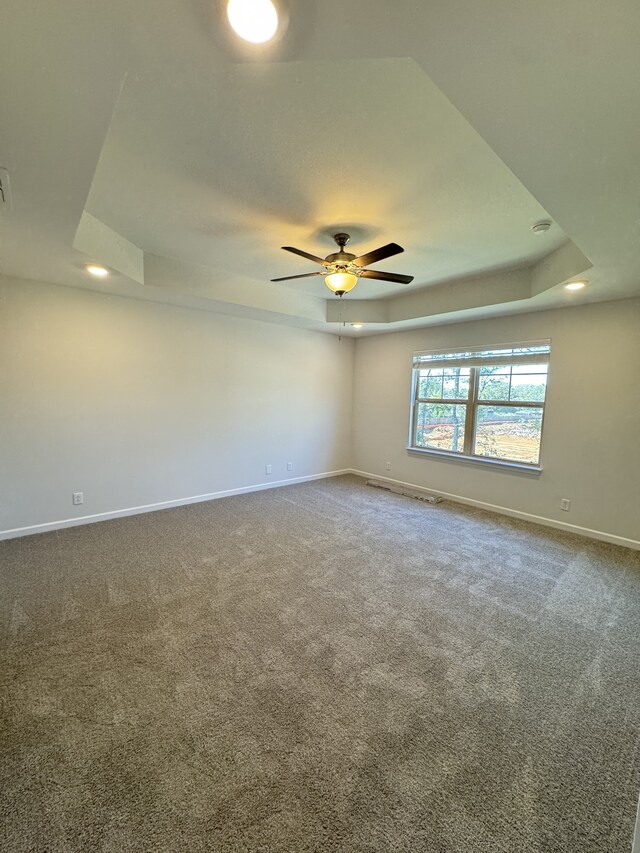 unfurnished room featuring carpet, baseboards, and a raised ceiling