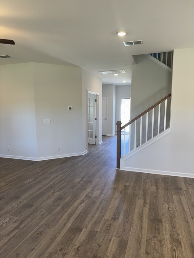 unfurnished room with dark wood-type flooring, visible vents, stairway, and baseboards