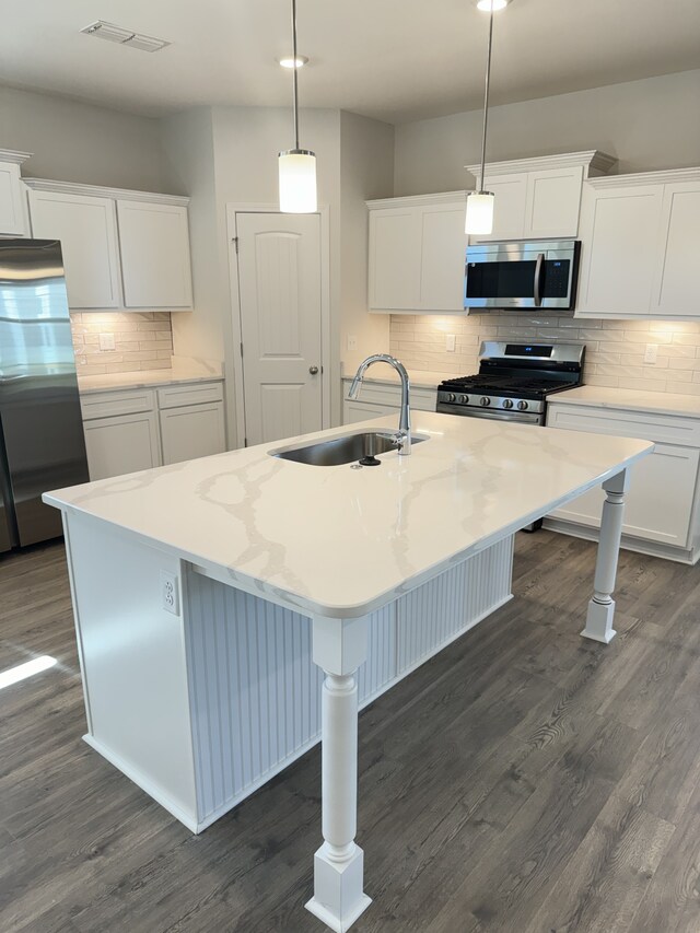 kitchen featuring dark wood-type flooring, a sink, visible vents, appliances with stainless steel finishes, and a center island with sink