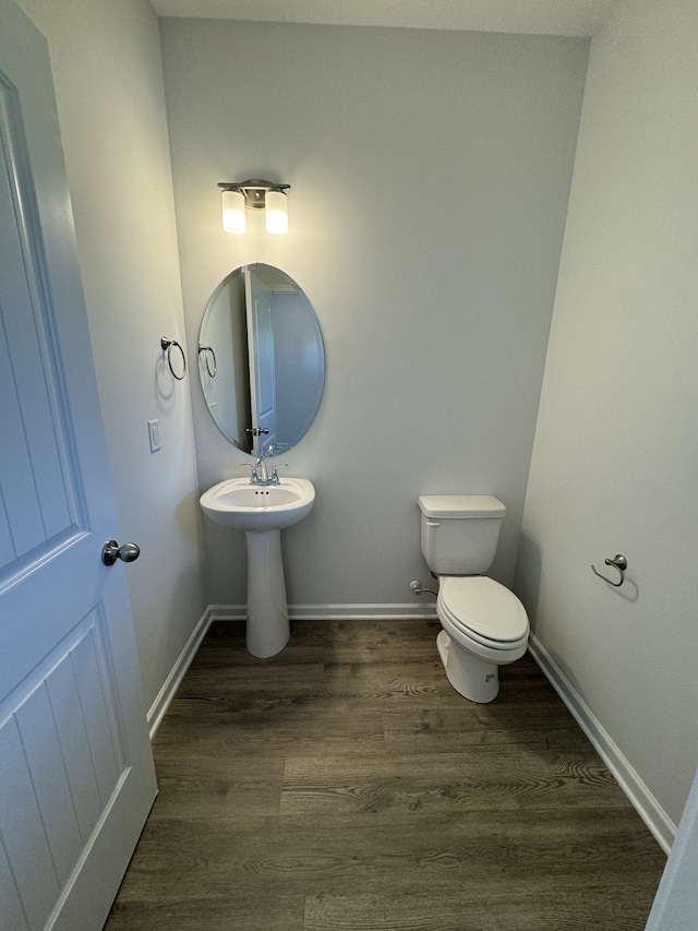 bathroom with baseboards, a sink, toilet, and wood finished floors