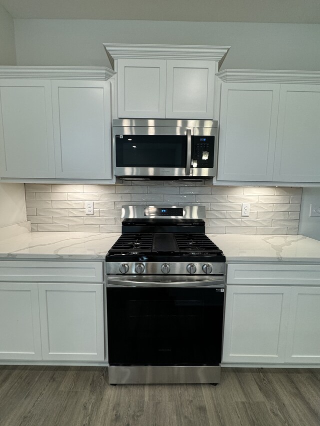 kitchen with tasteful backsplash, gas stove, stainless steel microwave, and wood finished floors