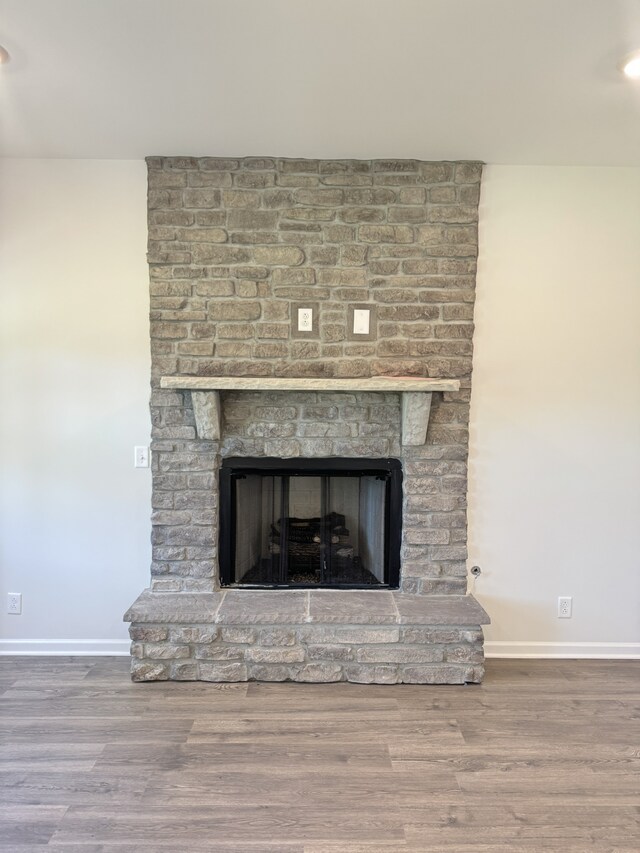 interior details featuring a brick fireplace, wood finished floors, and baseboards