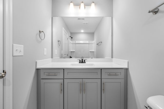 bathroom with visible vents, vanity, toilet, and a shower