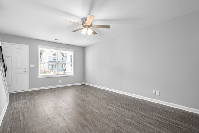 empty room featuring baseboards, dark wood-style flooring, and a ceiling fan