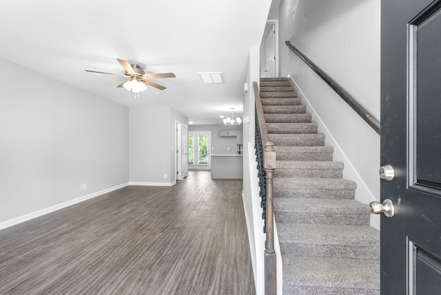 stairs with ceiling fan with notable chandelier, baseboards, and wood finished floors