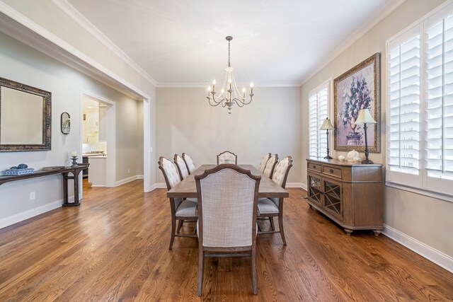 dining room featuring dark hardwood / wood-style flooring, an inviting chandelier, and crown molding