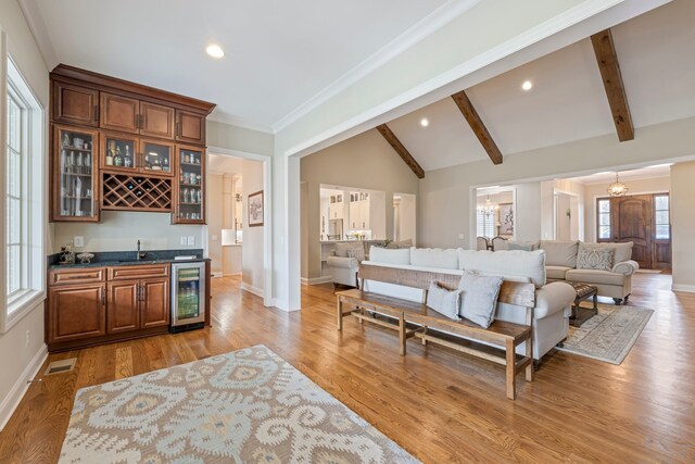 living room with sink, ornamental molding, wine cooler, light hardwood / wood-style flooring, and lofted ceiling with beams