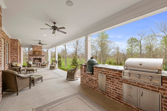 view of patio with exterior fireplace, ceiling fan, grilling area, and exterior kitchen