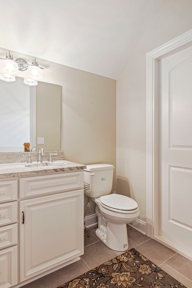 bathroom with tile flooring, toilet, vanity, and vaulted ceiling