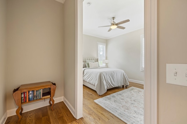 bedroom featuring light hardwood / wood-style flooring, ceiling fan, and ornamental molding