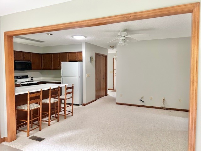 kitchen with light carpet, white appliances, ceiling fan, and dark brown cabinets