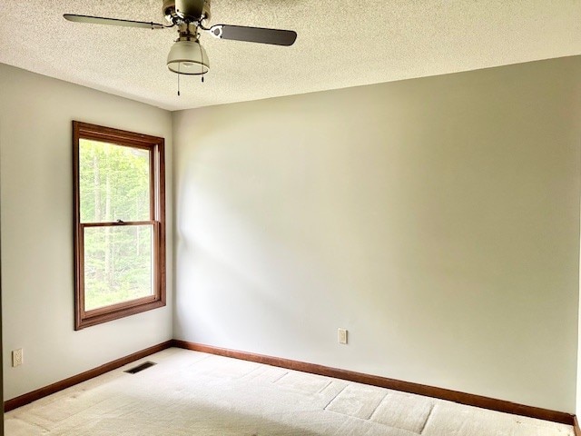 spare room featuring a wealth of natural light, carpet floors, ceiling fan, and a textured ceiling