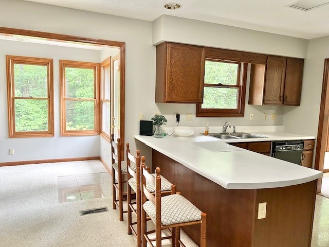 kitchen featuring light tile flooring, kitchen peninsula, a breakfast bar area, black dishwasher, and sink