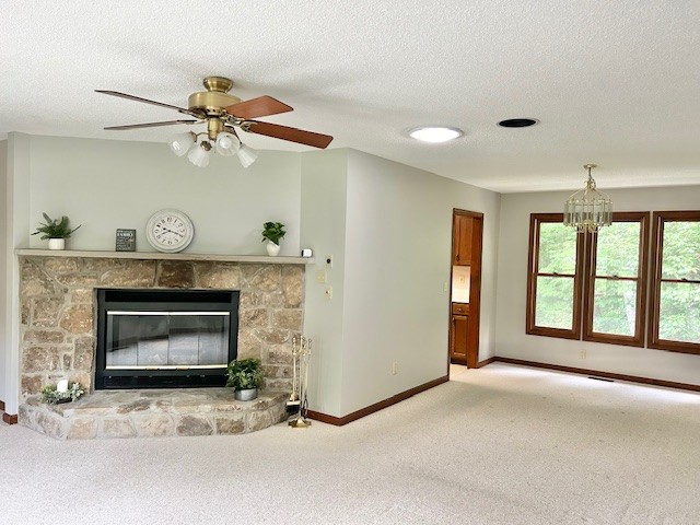 unfurnished living room with a textured ceiling, a fireplace, carpet, and ceiling fan