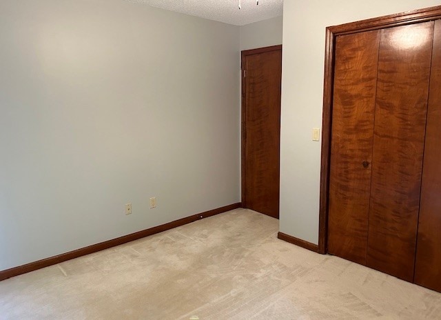 unfurnished bedroom with a textured ceiling, a closet, and carpet