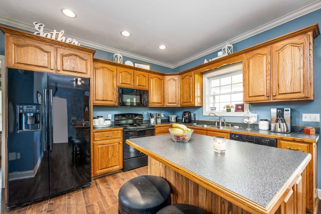 kitchen featuring a kitchen island, crown molding, black appliances, hardwood / wood-style floors, and sink