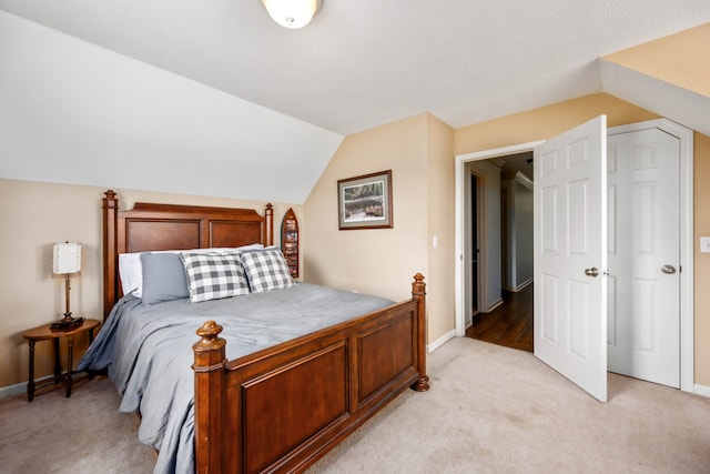 bedroom with light colored carpet, a textured ceiling, and lofted ceiling