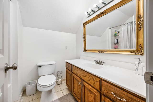 bathroom with toilet, large vanity, tile floors, and vaulted ceiling