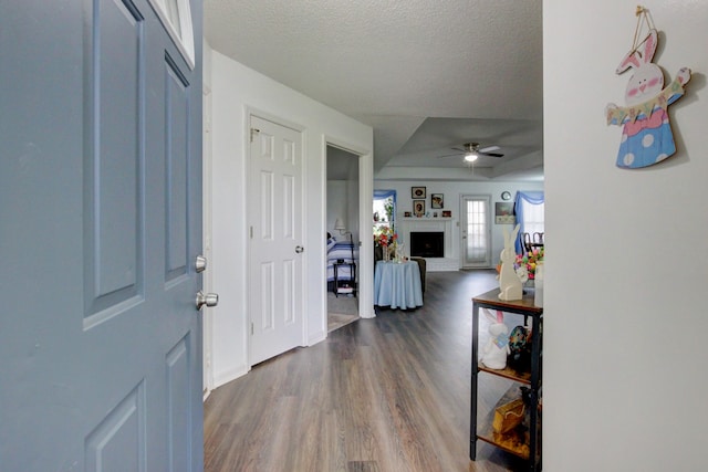 entrance foyer featuring ceiling fan, dark wood-type flooring, a fireplace, and a textured ceiling