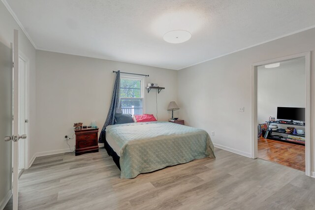 bedroom with light hardwood / wood-style floors, crown molding, and a textured ceiling